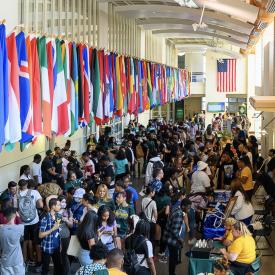 NJCU Open house in the Gilligan student union building. Potential students are speaking with each other and various departments of NJCU with flags of various countries shown hung above along the walls to represent NJCU's diverse population.