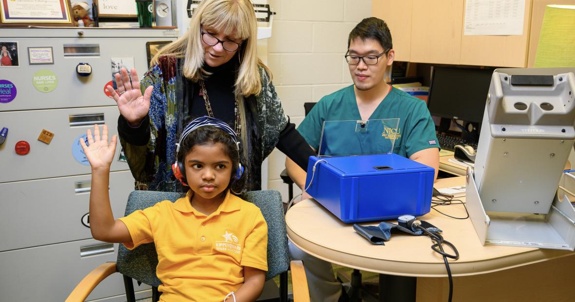 Nursing students administer a hearing test to a child patient