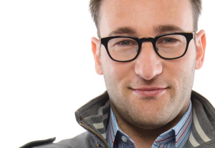 portrait of a young Caucasian male with black-framed glasses dressed in a gray jacket with a blue-collared shirt showing 