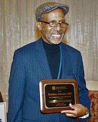 MATTHEW B JOHNSON POSES WITH PLAQUE