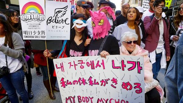 WOMEN STANDING WITH PROTEST SIGNAGE