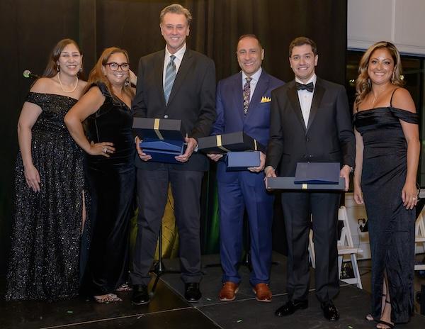 six adults pose in formal wear holding awards